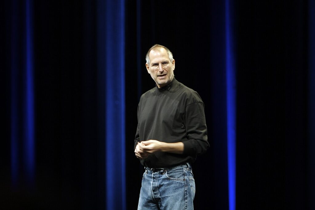 Steve Jobs on stage at an Apple product launch in his typical black turtleneck and jeans