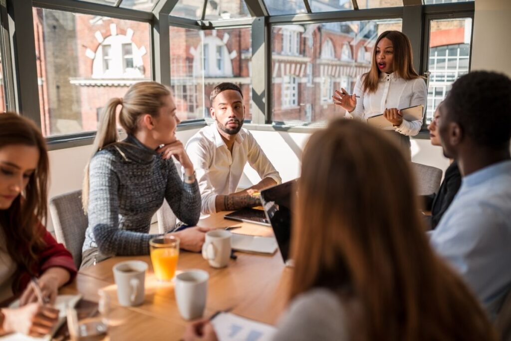 Group of communications people sitting around a table in a meeting room conducting an exercise