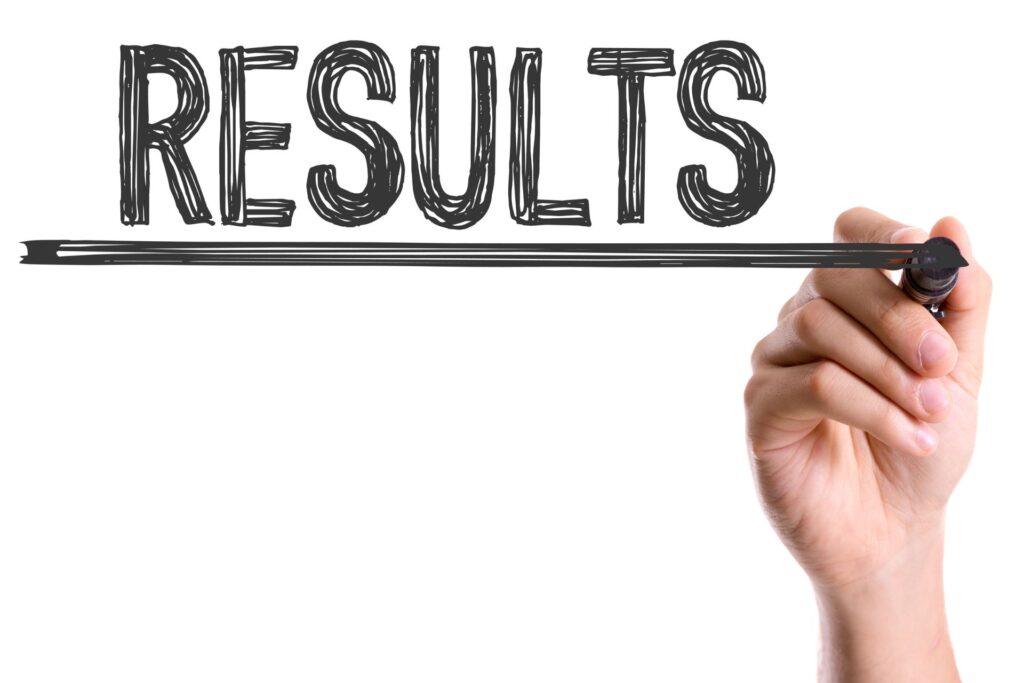 Hand scrawling the word Results across a whiteboard