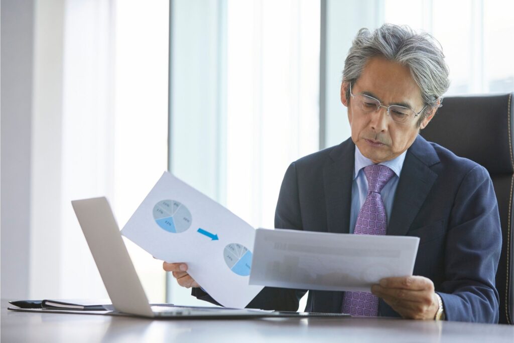 Well-dressed executive at a boardroom table reading printed pages of a report